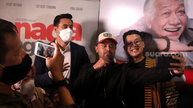 Pemain film Naga Naga Naga, Darius Sinathrya (kedua kiri), Mike Muliadro (tengah), dan Uli Herdinansyah berswafoto saat ditemui Epicentrum XXI, Jakarta, Rabu (8/6/2022). [Suara.com/Angga Budhiyanto]