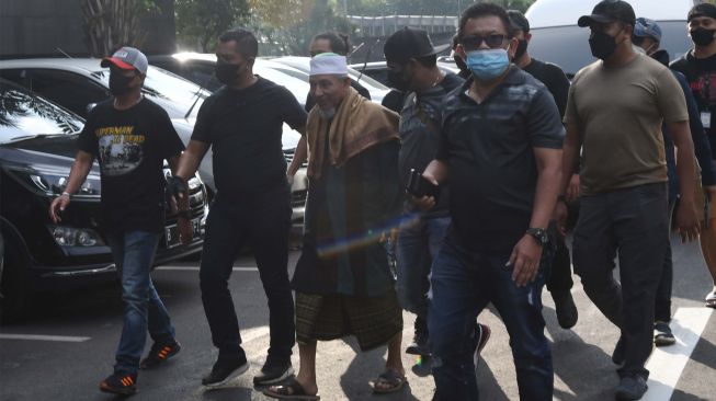 Sejumlah polisi mengamankan kedatangan pimpinan Khilafatul Muslimin, Abdul Qadir Baraja (ketiga kiri) saat tiba di Polda Metro Jaya, Jakarta, Selasa (7/6/2022). [ANTARA FOTO/Aditya Pradana Putra/foc]
