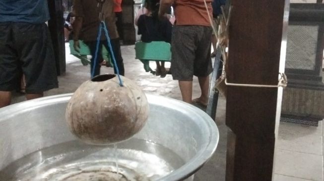 Tempurung kelapa diisi air sebagai timer waktu pemutaran ayunan di Desa Adat Munggu, Mengwi, Badung, Bali. Setiap pengunjung hanya boleh menggunakan selama 3 menit. [Foto : Suara.com/Yosef Rian] 