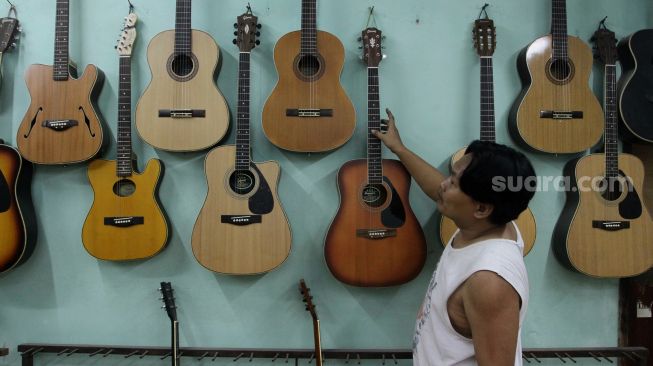 Pekerja menata gitar di sentra produksi dan reparasi gitar Pak Manto di Jalan Langgar II, Pejaten Timur, Pasar Minggu, Jakarta, Kamis (9/6/2022). [Suara.com/Angga Budhiyanto]