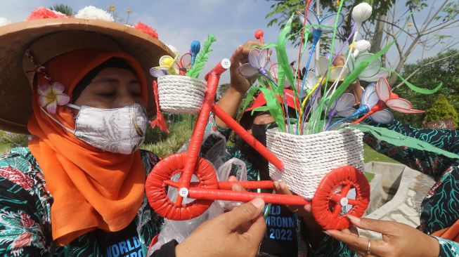 Perserta merangkai hiasan rumah berbentuk sepeda berbahan baku kantong plastik bekas saat lomba daur ulang sampah di Taman Totok Kerot, Kediri, Jawa Timur, Kamis (9/6/2022).  ANTARA FOTO/Prasetia Fauzani
