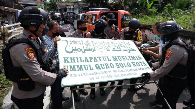 Polisi menurunkan papan bertulis Khilafatul Muslimin dari rumah warga sekaligus kantor cabang kelompok tersebut di Solo, Jawa Tengah, Kamis (9/6/2022). ANTARAFOTO/Maulana Surya
