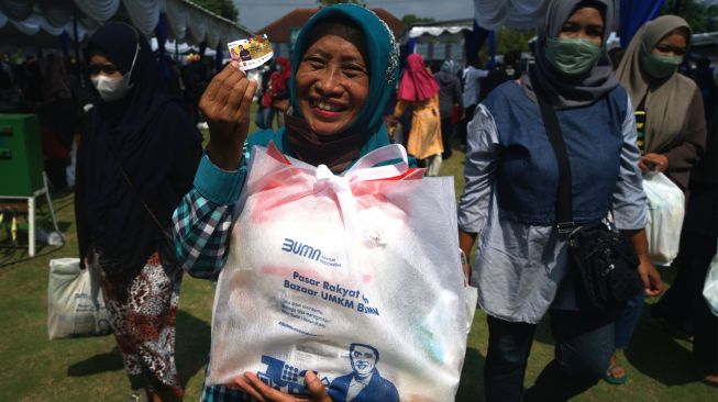 Warga menunjukan paket sembako saat penyaluran paket sembako BUMN di Lapangan Paseban, Bantul, D.I Yogyakarta, Sabtu (11/6/2022). [ANTARA FOTO/Andreas Fitri Atmoko/foc]