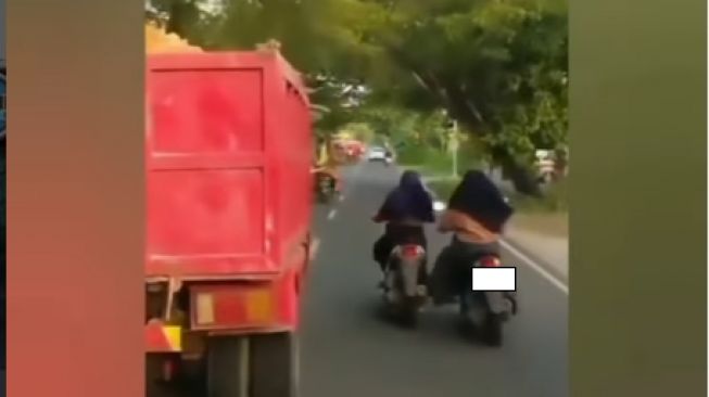 Emak-emak sambil dorong motor rekannya yang mogok dan salip truk di jalan (Instagram)