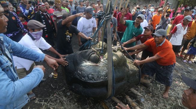 Pekerja mengangkat kepala arca Kala menggunakan alat berat dari sungai di Desa Nambaan, Kediri, Jawa Timur, Minggu (12/6/2022). ANTARA FOTO/Prasetia Fauzani