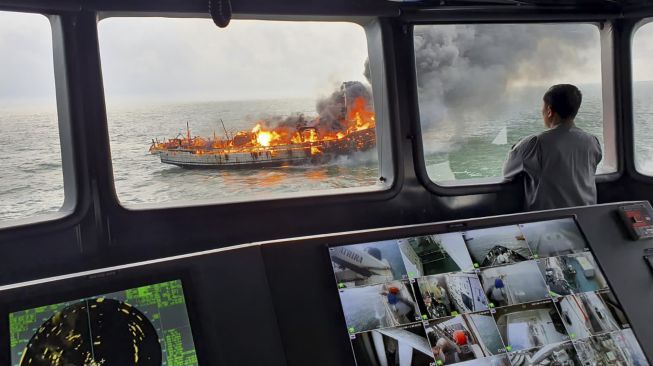 Personel Badan Keamanan Laut (Bakamla) awak KN Pulau Dana-323 mengamati KM Bintang Surya yang terbakar di Perairan Karimun, Selat Malaka, Riau, Minggu (12/6/2022).  ANTARA FOTO/Humas Bakamla RI