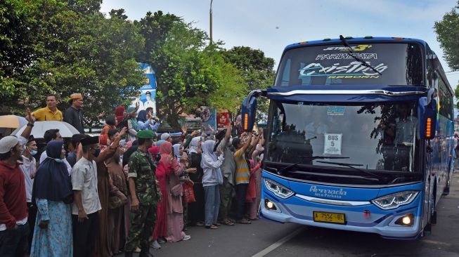 Sejumlah warga melambaikan tangan kepada jemaah calon haji di dalam bis saat diberangkatkan dari Alun-alun Serang, Banten, Minggu (12/6/2022). ANTARA FOTO/Asep Fathulrahman
