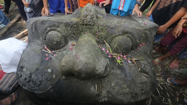 Sejumlah warga mengamati kepala arca Kala usai diangkat dari sungai di Desa Nambaan, Kediri, Jawa Timur, Minggu (12/6/2022).  ANTARA FOTO/Prasetia Fauzani