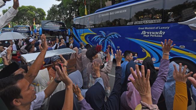 Sejumlah warga melambaikan tangan kepada jemaah calon haji di dalam bis saat diberangkatkan dari Alun-alun Serang, Banten, Minggu (12/6/2022). ANTARA FOTO/Asep Fathulrahman
