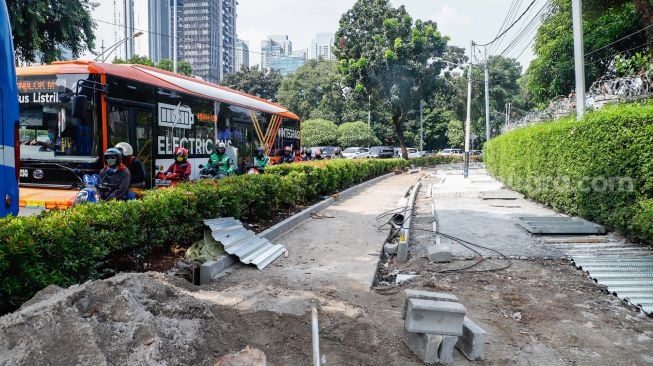 Pekerja menyelesaikan proyek revitalisasi trotoar di Jalan Pattimura, Jakarta Selatan, Senin (13/6/2022). [Suara.com/Alfian Winanto]