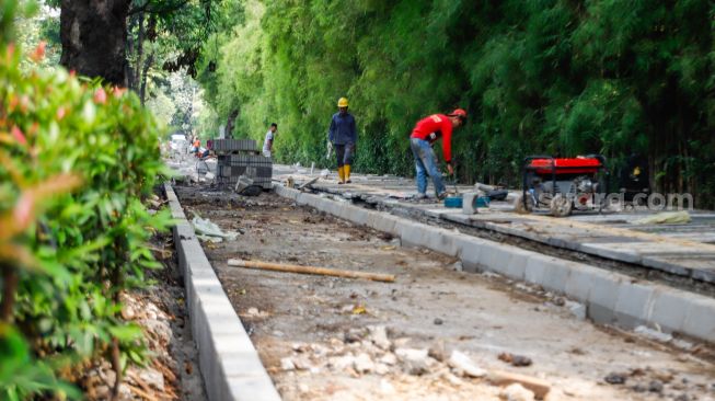 Pekerja menyelesaikan proyek revitalisasi trotoar di Jalan Pattimura, Jakarta Selatan, Senin (13/6/2022). [Suara.com/Alfian Winanto]