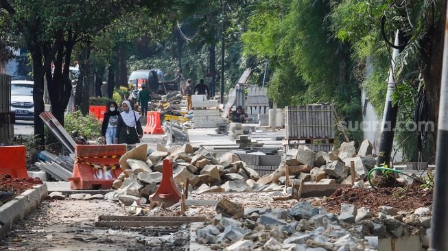 Pekerja menyelesaikan proyek revitalisasi trotoar di Jalan Pattimura, Jakarta Selatan, Senin (13/6/2022). [Suara.com/Alfian Winanto]