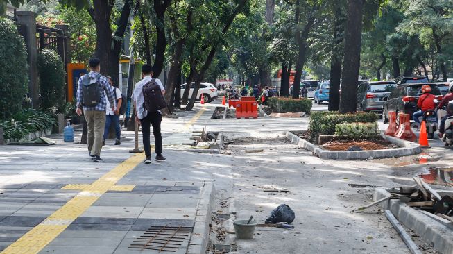 Pekerja menyelesaikan proyek revitalisasi trotoar di Jalan Pattimura, Jakarta Selatan, Senin (13/6/2022). [Suara.com/Alfian Winanto]