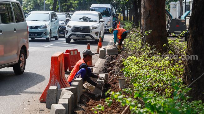 Pekerja menyelesaikan proyek revitalisasi trotoar di Jalan Pattimura, Jakarta Selatan, Senin (13/6/2022). [Suara.com/Alfian Winanto]