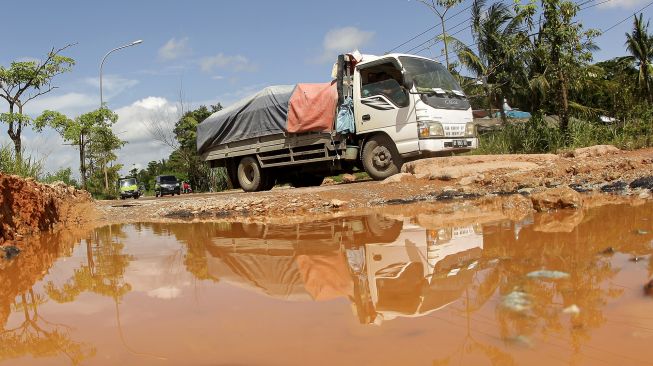 Truk melintasi jalan lintas industri yang rusak dan berlubang di Kabil, Batam, Kepulauan Riau, Selasa (14/6/2022).  ANTARA FOTO/Teguh Prihatna