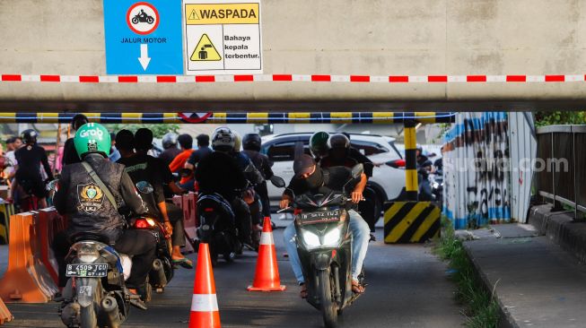 Pengendara motor melintas di Jembatan Antelope, Curug, Bekasi, Jawa Barat, Selasa (14/6/2022). [Suara.com/Alfian Winanto]