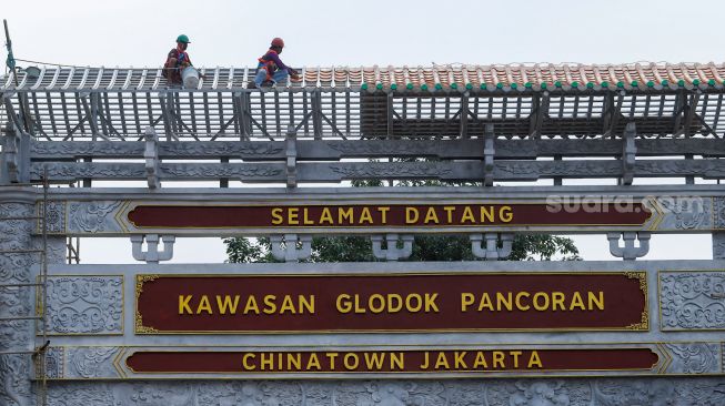 Pekerja menyelesaikan pembangunan konstruksi proyek gapura Chinatown di Glodok, Jakarta Barat, Selasa (14/6/2022). [Suara.com/Alfian Winanto]