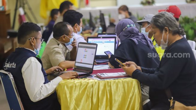 Petugas melayani warga yang berkonsultasi terkait pendaftaran daring Penerimaan Peserta Didik Baru (PPDB) 2022 di Posko Pelayanan PPDB SMA Negeri 70 Jakarta Selatan, Jakarta, Selasa (14/6/2022). [Suara.com/Alfian Winanto]