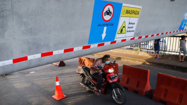 Pengendara motor melintas di Jembatan Antelope, Curug, Bekasi, Jawa Barat, Selasa (14/6/2022). [Suara.com/Alfian Winanto]