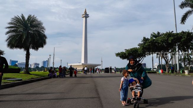 Warga berwisata mengunjungi Monumen Nasional (Monas) di Gambir, Jakarta Pusat, Kamis (16/6/2022). [Suara.com/Alfian Winanto]