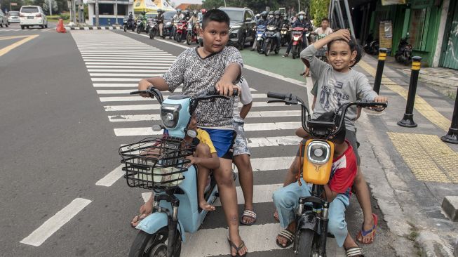 Sejumlah bocah mengendarai motor listrik di jalan raya di Jakarta, Kamis (16/6/2022).  ANTARA FOTO/Muhammad Adimaj