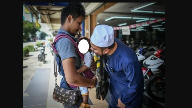 Pria bekerja mengantarkan makanan dengan menggending bocah mendapat perhatian dari ustaz (Facebook)