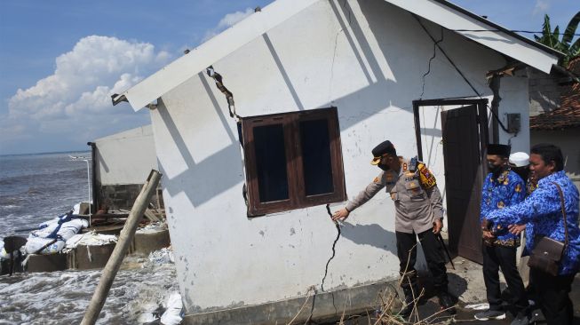 Kapolres Situbondo AKBP Andi Sinjaya (kiri) meninjau rumah warga yang rusak terkena banjir rob atau air laut pasang di Desa Landangan, Kapongan, Situbondo, Jawa Timur, Jumat (17/6/2022). [ANTARA FOTO/Seno/foc]