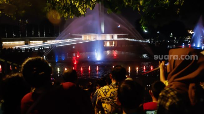 Warga menonton pertunjukan air mancur di Taman Lapangan Banteng, Jakarta Pusat, Sabtu (18/6/2022). [Suara.com/Alfian Winanto]