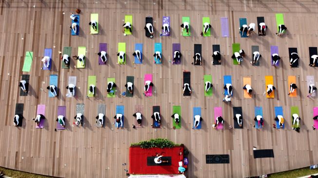 Foto udara warga melakukan gerakan yoga di Pulau Wangi Pantai Boom, Banyuwangi, Jawa Timur, Minggu (19/6/2022).  ANTARA FOTO/Budi Candra Setya