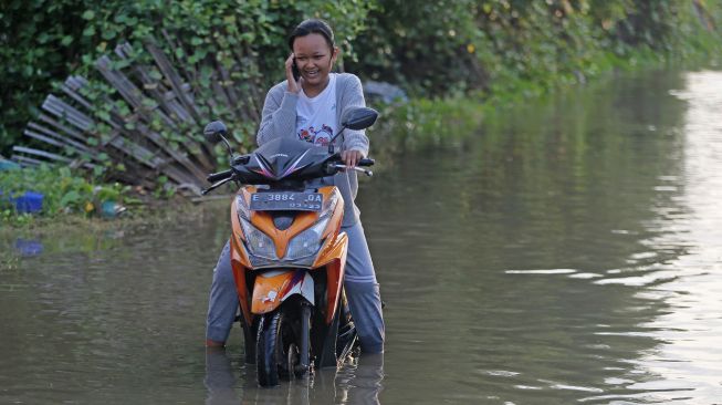 Sejumlah pengendara kendaraan bermotor melintasi banjir rob di Karangsong, Indramayu, Jawa Barat, Senin (20/6/2022). ANTARA FOTO/Dedhez Anggara