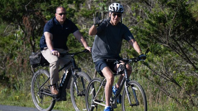 Presiden Amerika Serikat Joe Biden menyapa pendukungnya dari sepeda pada Sabtu (18/6/2022). [AFP/Photo]