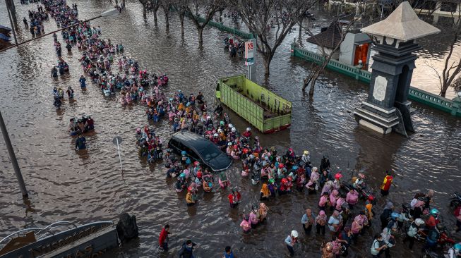 Foto udara ratusan pekerja industri kawasan pelabuhan berjalan menembus banjir limpasan air laut ke daratan atau rob yang merendam kawasan Pelabuhan Tanjung Emas Semarang, Jawa Tengah, Senin (20/6/2022).  ANTARA FOTO/Aji Styawan