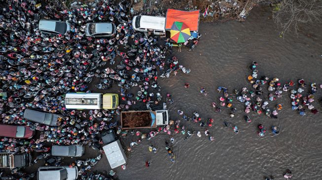 Foto udara ratusan pekerja industri kawasan pelabuhan berjalan menembus banjir limpasan air laut ke daratan atau rob yang merendam kawasan Pelabuhan Tanjung Emas Semarang, Jawa Tengah, Senin (20/6/2022).  ANTARA FOTO/Aji Styawan