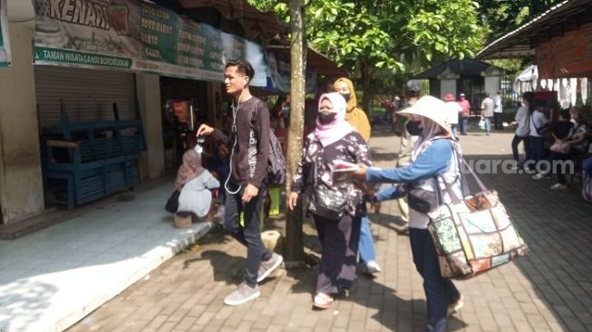 Kartini menawarkan kaos Borobudur dagangaannya kepada wisatawan. Berebut rupiah di area berdagang dan parkir kompleks Candi Borobudur. [Suara.com/ Angga Haksoro Ardi]