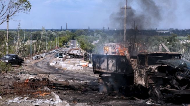 Sebuah truk terlihat hancur dan terbakar di jembatan yang menghubungkan Severodoonetsk dan Lysychansk, Luhansk, Ukraina Timur pada 28 Mei 2022. (FOTO: The Moscow Times/TASS)