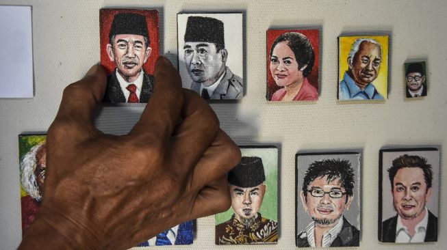 Seniman perupa Iwan Ridwan, menempelkan lukisan karyanya di Kimuri Art Studio, Kampung Bojongkaliki, Kecamatan Tarogong Kidul, Kabupaten Garut, Jawa Barat, Rabu (23/6/2022). ANTARA FOTO/Adeng Bustomi