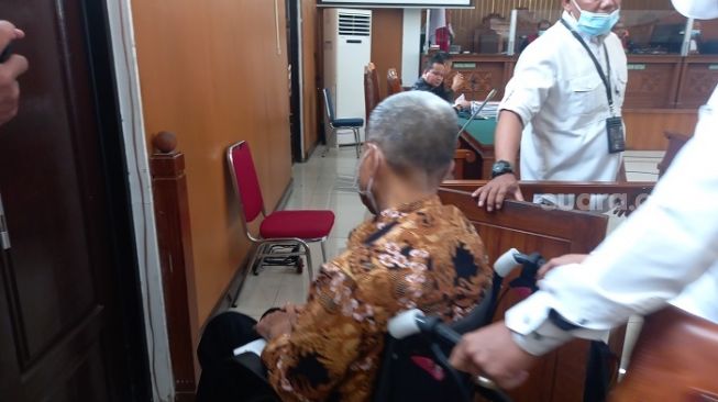 M Kece, korban penganiayaan di Rutan Bareskrim memakai kursi roda saat hadiri sidang kasus Irjen Napoleon Bonarparte di PN Jaksel, (Suara.com/Yosea Arga)