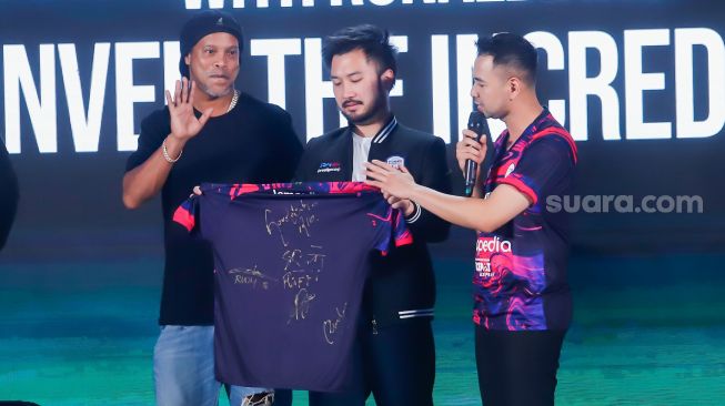 Legenda Sepak Bola Brazil, Ronaldinho (kiri) bersama Chairman RANS Nusantara FC, Raffi Ahmad (kanan) dan Rudy Salim (tengah) menunjukkan jersey baru untuk musim 2022-2023 di Jakarta, Jum'at (24/6/2022). [Suara.com/Alfian Winanto]