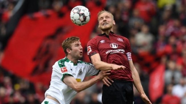 Hanno Behrens, saat memperkuat Nuremberg, berebut bola dengan pemain Borussia Moenchengladbach pada pertandingan Bundesliga yang digelar 5 November 2019. [AFP]