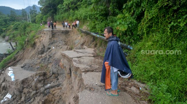 Warga berada di ujung jalan yang amblas di Nagari Sungai Buluh Timur, Kabupaten Padangpariaman, Sumatera Barat, Sabtu (25/6/2022). [ANTARA FOTO/Iggoy el Fitra/rwa]