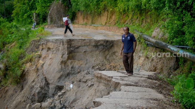 Warga berada di ujung jalan yang amblas di Nagari Sungai Buluh Timur, Kabupaten Padangpariaman, Sumatera Barat, Sabtu (25/6/2022). [ANTARA FOTO/Iggoy el Fitra/rwa]