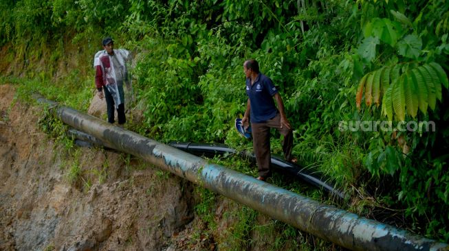 Warga dan pelajar berada di ujung jalan yang amblas di Nagari Sungai Buluh Timur, Kabupaten Padangpariaman, Sumatera Barat, Sabtu (25/6/2022). [ANTARA FOTO/Iggoy el Fitra/rwa]
