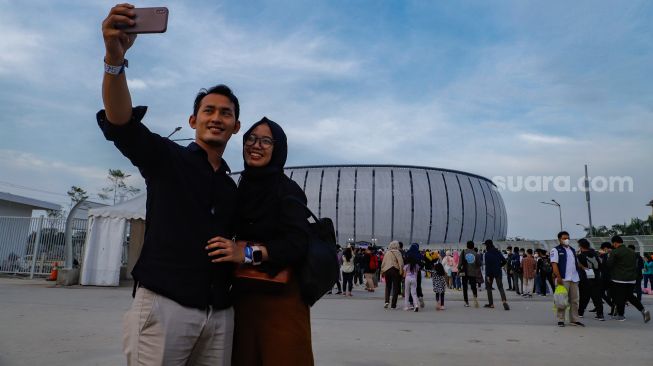 Warga berfoto dengan latar belakang Jakarta International Stadium (JIS), Sunter, Jakarta Utara, Sabtu (25/6/2022). [Suara.com/Alfian Winanto]
