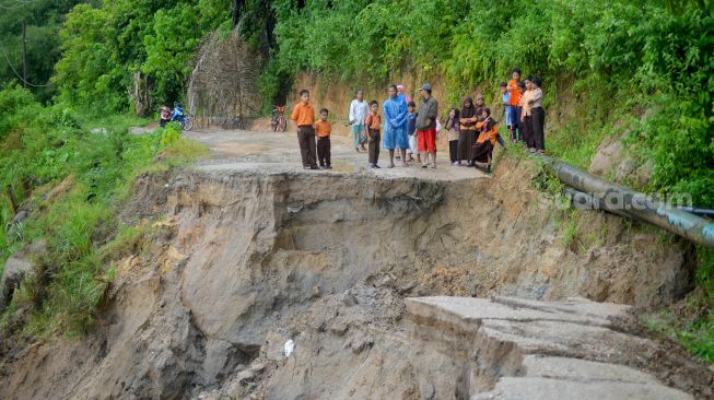 Warga dan pelajar berada di ujung jalan yang amblas di Nagari Sungai Buluh Timur, Kabupaten Padangpariaman, Sumatera Barat, Sabtu (25/6/2022). [ANTARA FOTO/Iggoy el Fitra/rwa]
