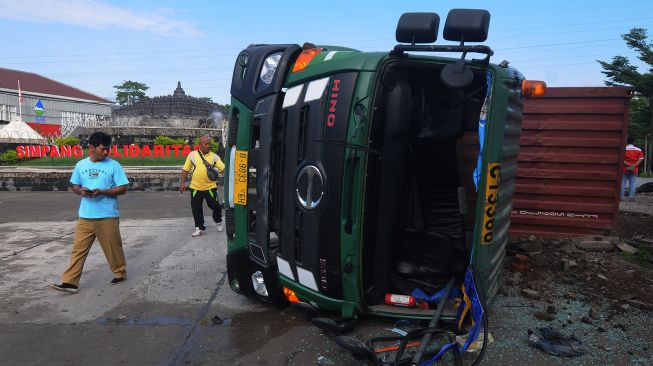 Warga melihat kondisi bangkai truk kontainer yang terguling karena kecelakaan di Simpang Solidaritas, Boyolali, Jawa Tengah, Senin (27/6/2022).  ANTARA FOTO/Aloysius Jarot Nugroho