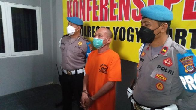 Tersangka berinisial KM saat digelandang polisi atas kasus pencabulan yang dilakukannya saat konferensi pers di Mapolresta Yogyakarta, Senin (27/6/2022). [dok.Humas Polresta Yogyakarta]