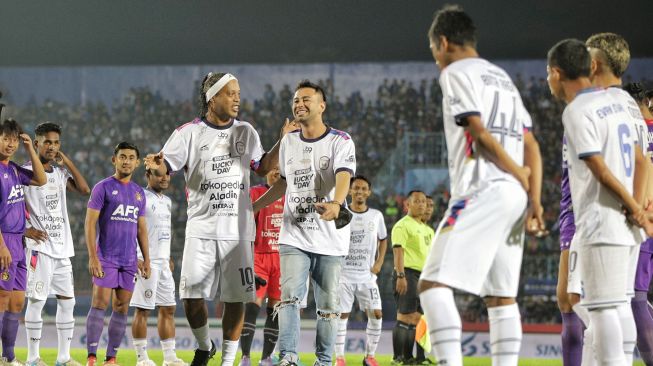 Mantan pesepak bola dunia asal Brazil Ronaldinho (tengah) berjalan dengan Chairman RANS Nusantara FC Raffi Ahmad saat membuka pertandingan Trofeo Ronaldinho di Stadion Kanjuruhan, Malang, Jawa Timur, Minggu (26/6/2022).  ANTARA FOTO/Rizal Hanafi