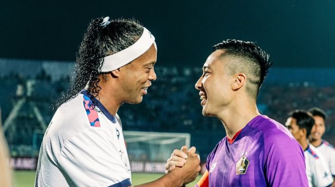 Pemain Persik Kediri, Arthur Irawan (kanan) berjabat tangan dengan legenda sepak bola Brasil, Ronaldinho dalam ajang Trofeo Nusantara di Stadion Kanjuruhan, Malang, Minggu (26/6/2022) malam WIB. [Persik Kediri]