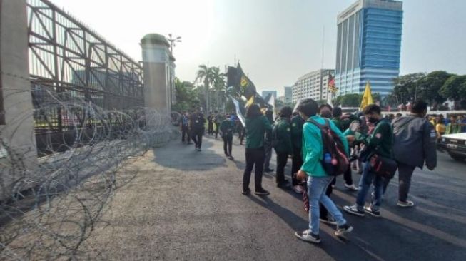 Massa pengunjuk rasa tiba di depan Gerbang Gedung DPR. Kawat berduri sepanjang pagar pembatas gedung wakil rakyat melintang saat aksi massa yang digelar pada Selasa (28/6/2022). [Suara.com/Yaumal]