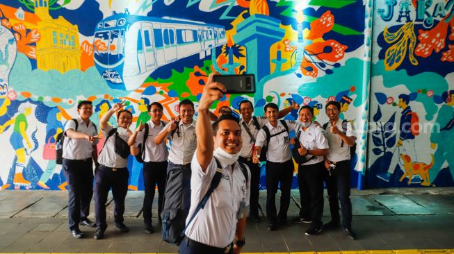 Warga berswafoto dengan latar belakang mural bertema Jakarta Kota Global di Terowongan Kendal, Jakarta Pusat, Senin (27/6/2022). [Suara.com/Alfian Winanto]